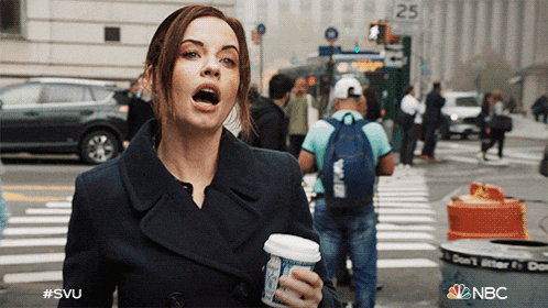 a woman holding a cup of coffee in front of a sign that says 25 on it