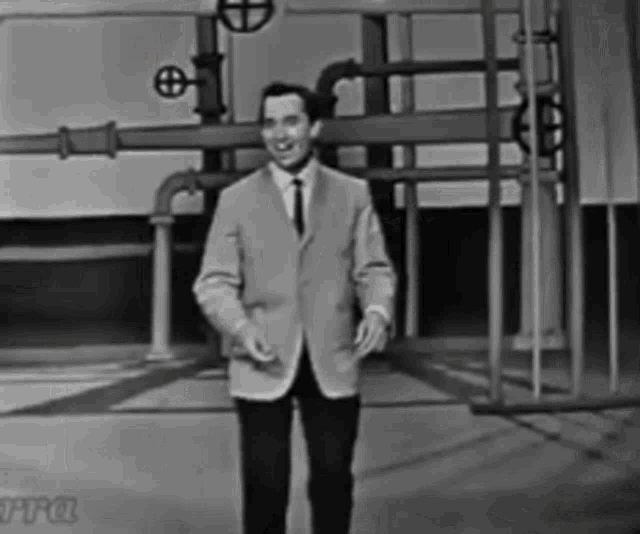 a man in a suit and tie stands in front of pipes