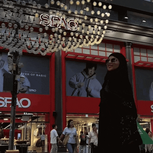 a woman in a hijab walks in front of a store that says spao