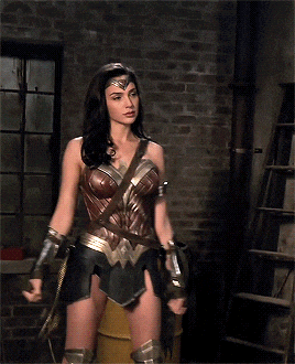 wonder woman is standing in front of a brick wall