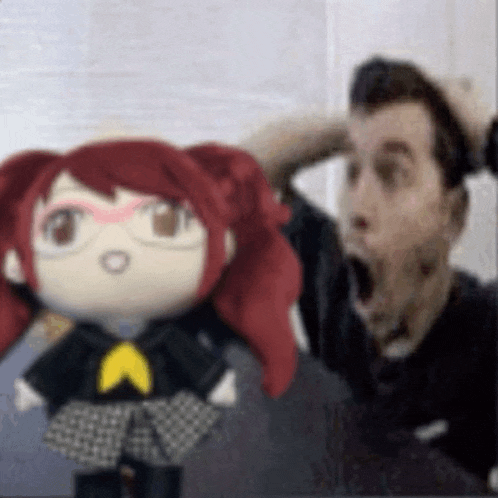 a man is holding his head in front of a stuffed doll with red hair