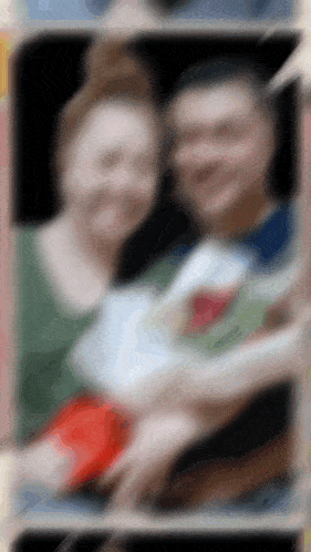 a blurry picture of a man and woman holding a baby