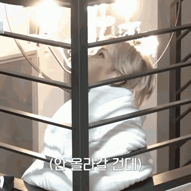 a person in a white hoodie is behind a metal railing