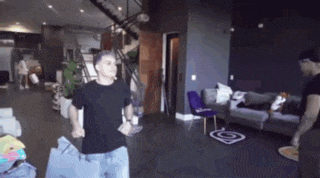a man in a black shirt is standing in a living room holding a bag