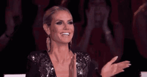 a woman in a sequined dress is clapping her hands in a crowd .