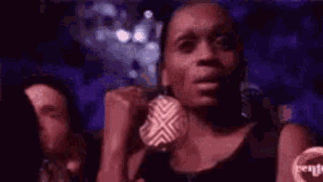a woman is holding a microphone in her hand and making a face .