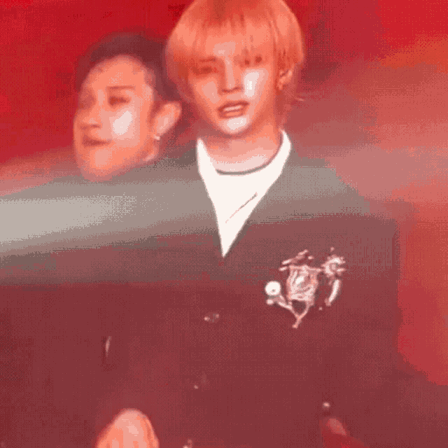 a man with blonde hair is standing next to another man on a stage .