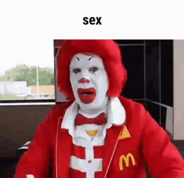 a clown dressed as mcdonald 's donald duck is standing in front of a window in a room .