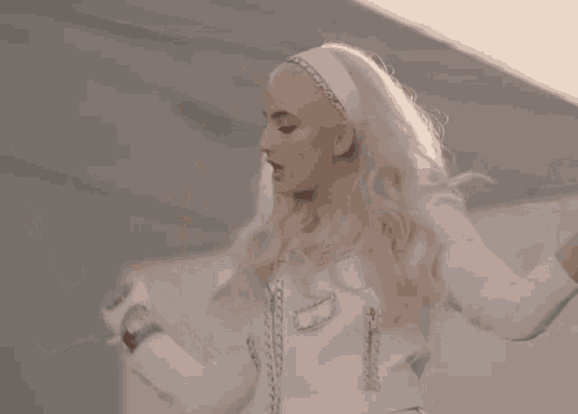 a blonde woman wearing a white jacket and a headband is dancing .