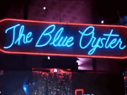 a neon sign for the blue oyster hangs from the ceiling