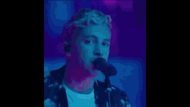 a man is singing into a microphone on a stage in front of a crowd .