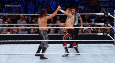 two wrestlers giving each other a high five in a wrestling ring .