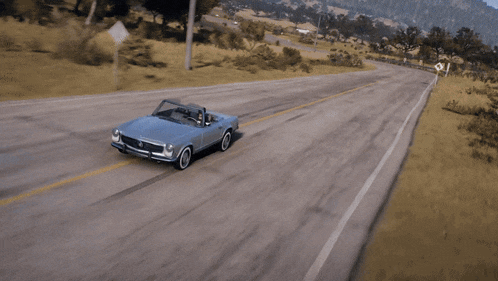 a silver convertible car with the top down is driving down a road