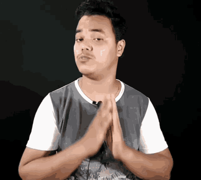 a man wearing a gray shirt and a white t-shirt is praying