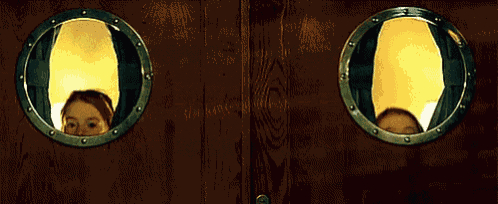 a woman looks out of a round window on a door
