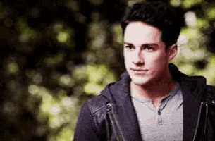 a young man wearing a leather jacket and a gray shirt