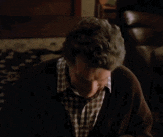 a man with gray hair and a plaid shirt is smiling in a dark room