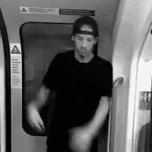 a man wearing a baseball cap is standing in a subway car .