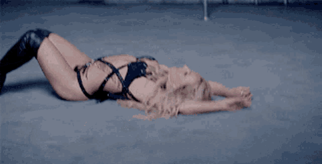 a woman in a black bodysuit is laying on the ground