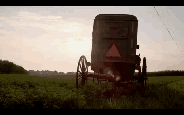 a horse drawn carriage is parked in a field