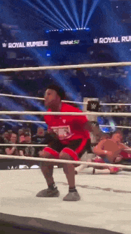 a young boy is squatting in a wrestling ring at a royal rumble event .