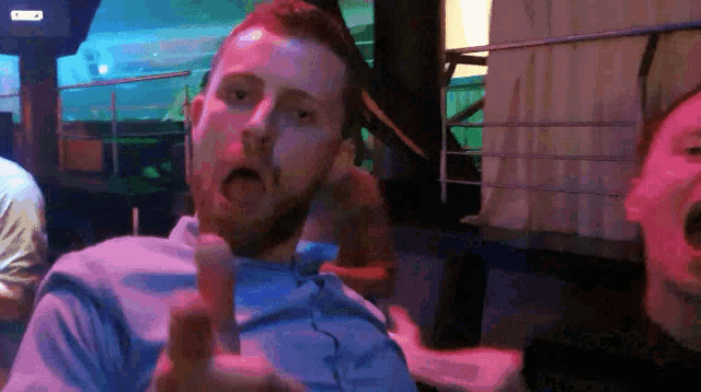 a man in a blue shirt is making a funny face