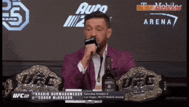 a man in a purple suit is talking into a microphone in front of a sign that says autozone arena