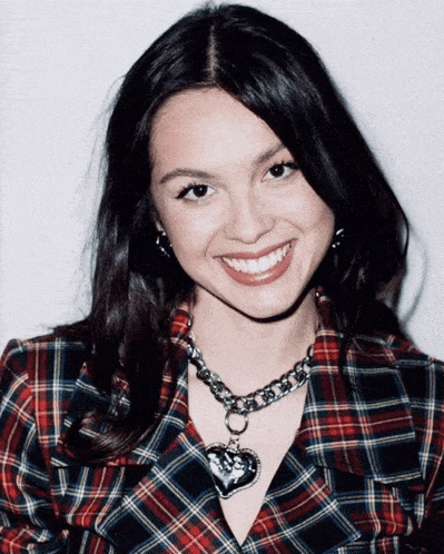 a woman wearing a plaid shirt and a necklace with a heart pendant
