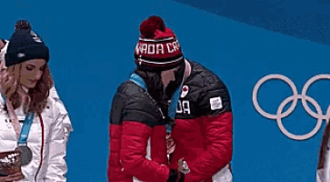 a woman wearing a hat that says canada on it is kissing another woman