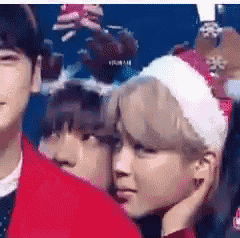 a man wearing a santa hat is standing next to another man .