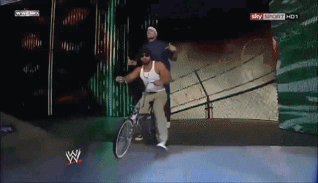 a man is riding a bike in front of a sign that says wwe hd