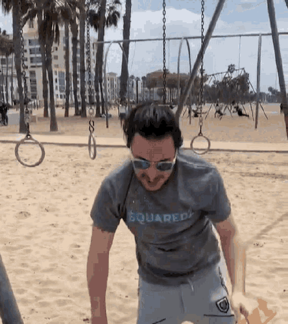 a man wearing sunglasses and a gray shirt that says squared