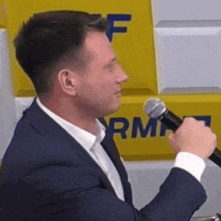 a man in a suit is holding a microphone in his hand .