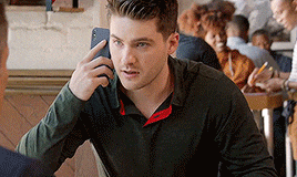 a man is sitting at a table in a restaurant talking on a cell phone .