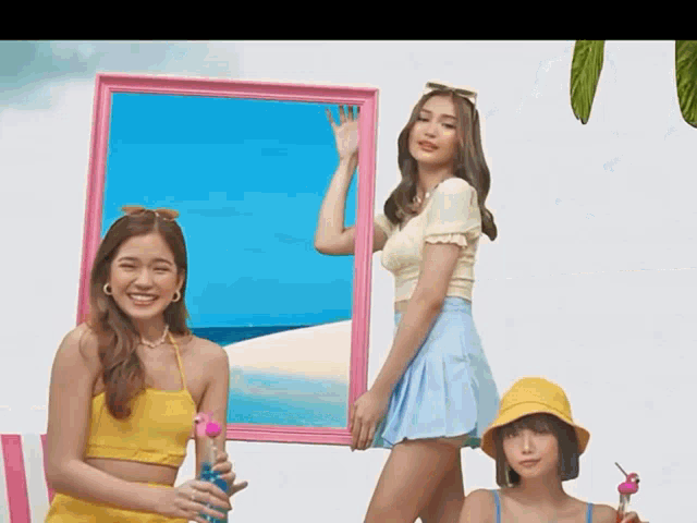 three young women are standing next to each other in front of a pink frame .