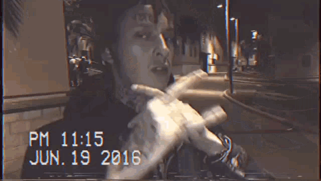 a man with a tattoo on his forehead is smoking a cigarette at night