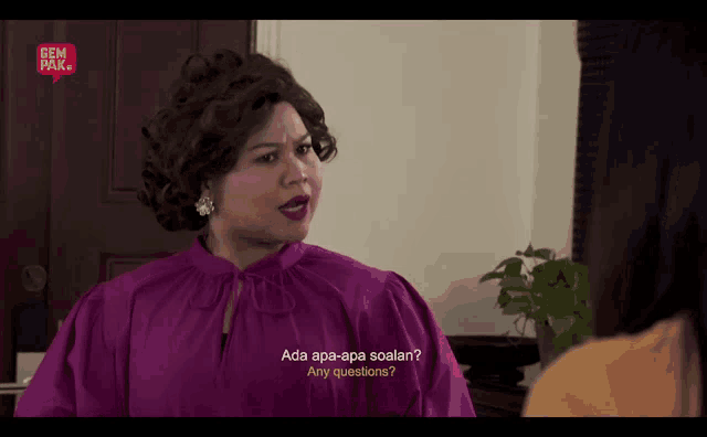 a woman in a purple shirt is talking to another woman and says " ada apa-apa soalan "