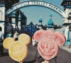 two mickey mouse ice creams are in front of a trolley park entrance
