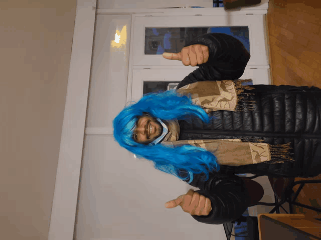 a man wearing a blue wig and a black jacket giving a thumbs up