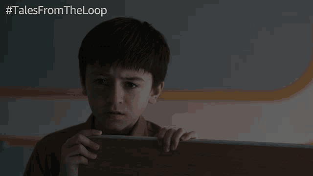 a young boy is holding a piece of wood with the word hi on it