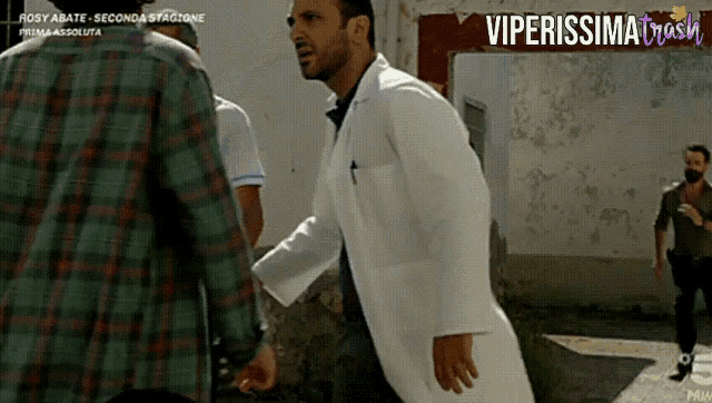 a man in a white coat stands in front of a sign that says viperissimo trash