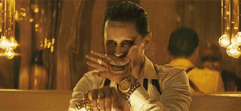 the joker from the movie suicide squad is wearing a watch and a gold ring .