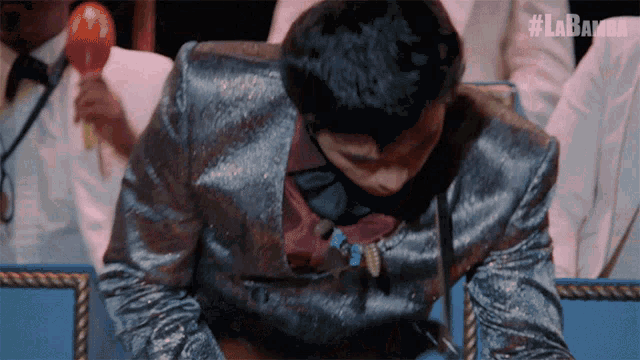 a man in a suit is sitting in front of a microphone with the hashtag #labamba on the bottom
