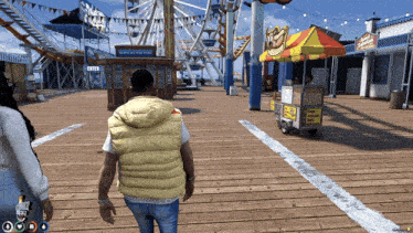 a man in a yellow vest walks down a wooden boardwalk in front of a ferris wheel at a carnival