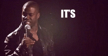 a man is holding a microphone in front of a sign that says `` it 's about to go ''