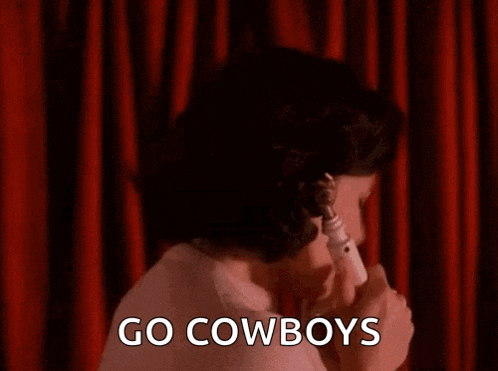 a woman is talking on a telephone in front of a red curtain and saying `` go cowboys '' .