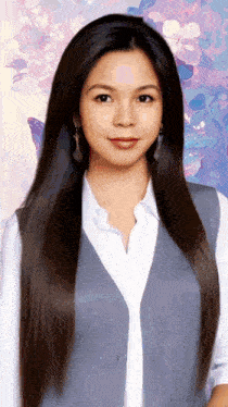 a woman with long hair is wearing a grey vest and a white shirt
