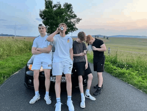 a group of young men are standing in front of a car with the license plate number 7u 392