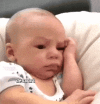 a baby is laying on a couch with his hand on his forehead