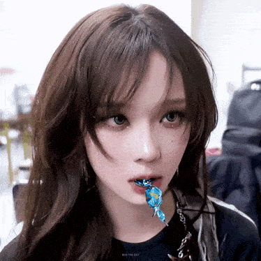 a girl with a blue candy in her mouth is wearing a shirt that says win the day on it